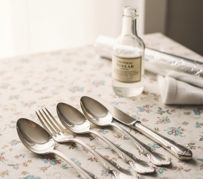 Couverts en argent vintage brillants avec une bouteille de vinaigre blanc.