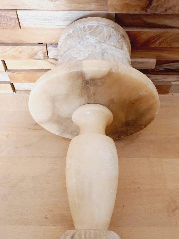 Lampe à poser italienne en albâtre de Volterra éteinte, posée sur un meuble en bois devant un mur de parement en bois. Pierre blanche et poreuse, créant une atmosphère cosy chic et chaleureuse.
