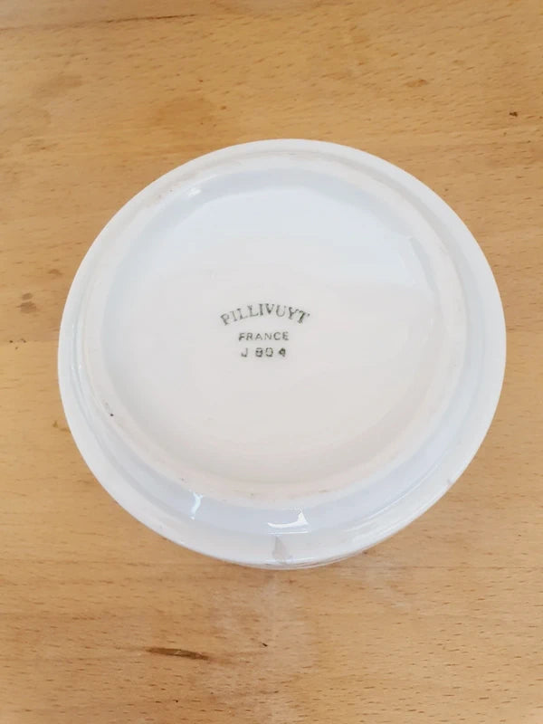Petite coupelle ronde en porcelaine blanche brillante avec l'inscription noire "Poubelle Apéritif" à l'intérieur et de fines fleurs colorées sur le bord extérieur.