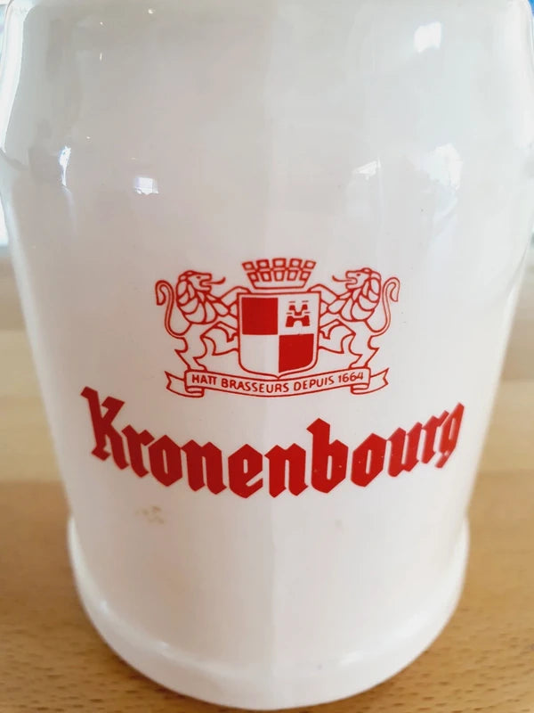 Petite choppe à bière vintage Kronenbourg en grès crème avec logo rouge et signature Baudoin RF Belgium gravée sous la base.