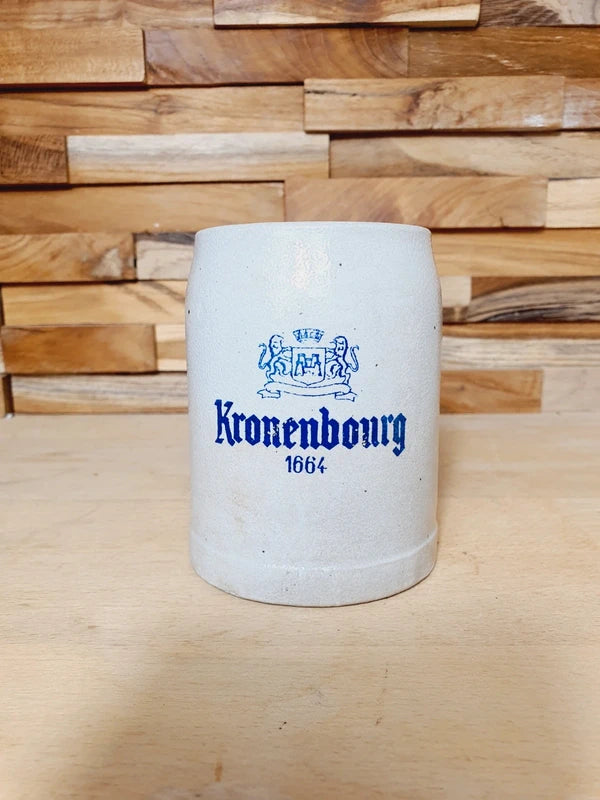Petite choppe à bière en grès gris et bleu cobalt avec logo Kronenbourg en relief, fabriquée en Allemagne, style traditionnel rustique.
