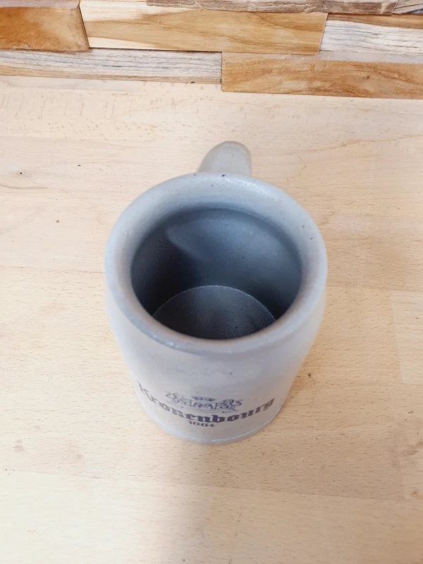 Petite choppe à bière en grès gris et bleu cobalt avec logo Kronenbourg en relief, fabriquée en Allemagne, style traditionnel rustique.