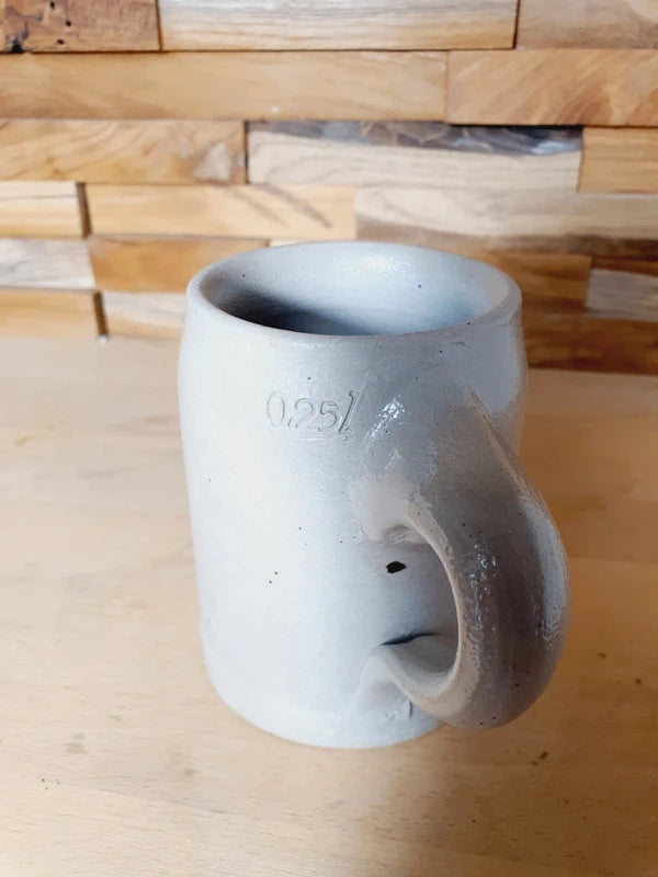 Petite choppe à bière en grès gris et bleu cobalt avec logo Kronenbourg en relief, fabriquée en Allemagne, style traditionnel rustique.
