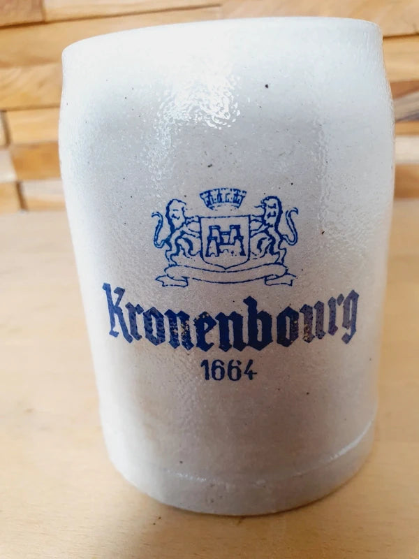 Petite choppe à bière en grès gris et bleu cobalt avec logo Kronenbourg en relief, fabriquée en Allemagne, style traditionnel rustique.