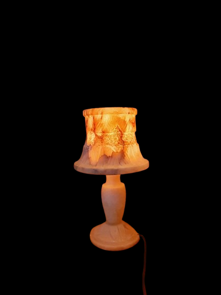 Lampe vintage en albâtre massif sculpté de 33 cm, style Hollywood Regency des années 60. sur fond neutre noir montrant le pied balustre et l'abat-jour minéral translucide illuminé d'une lumière chaude orangée.