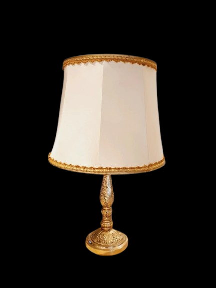 Lampe de table de style Regency & Art Français années 50-60. Hauteur 55,5 cm. Elle possède un pied en laiton sculpté combinant une base ornée. Son grand abat-jour en tissu de couleur crème est bordé de galons décoratifs. 