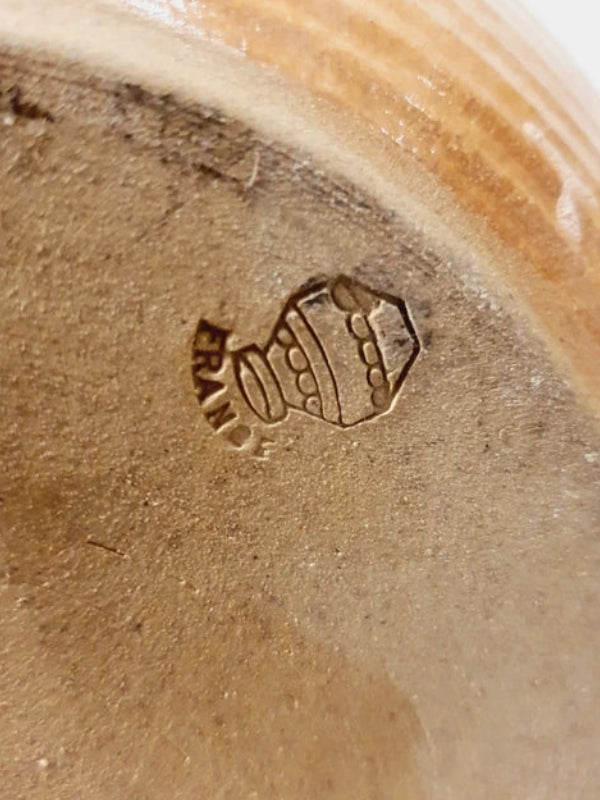 Une lampe vintage imposante composée d'un pied en grès français beige moucheté et d'un grand abat-jour en toile de jute tressée, diffusant une lumière chaude dans un intérieur à la décoration naturelle.