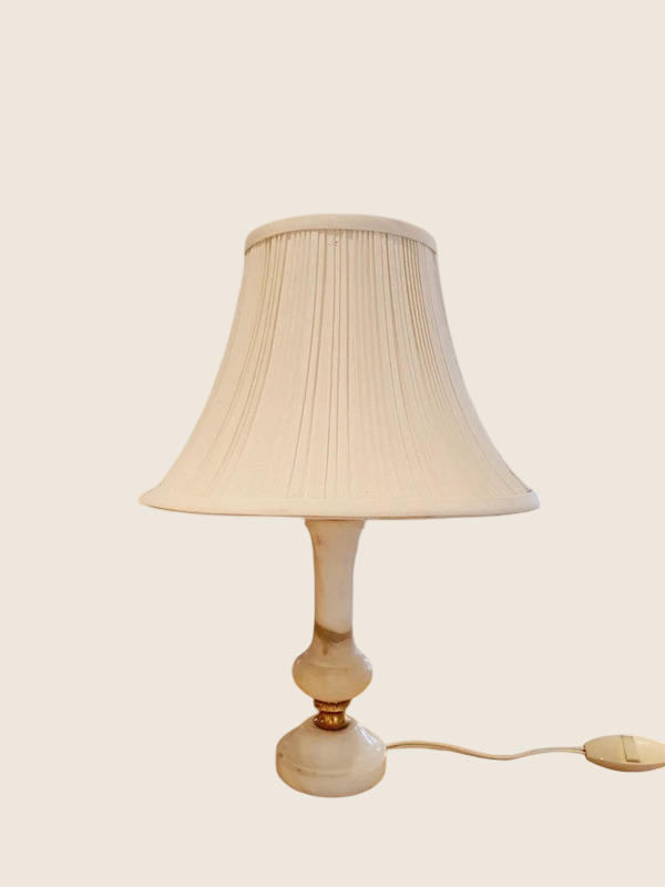 Petite lampe de chevet vintage avec un pied cylindrique en albâtre blanc veiné et un abat-jour plissé en tissu blanc.