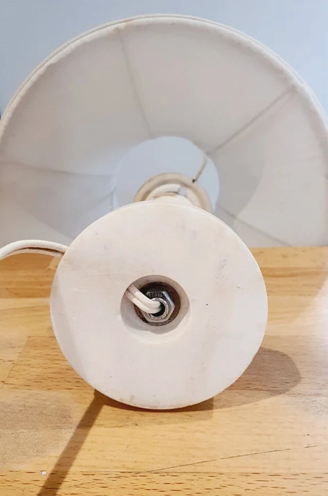 Petite lampe de chevet vintage avec un pied cylindrique en albâtre blanc veiné et un abat-jour plissé en tissu blanc, diffusant une lumière tamisée