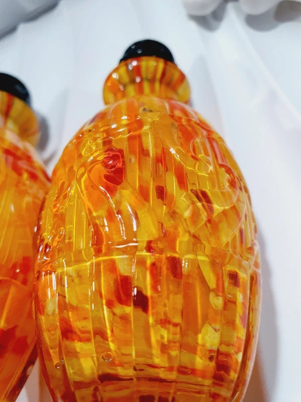 Duo de flacons de toilette Art Déco de 1930 en verre pressé moulé jaspé orange rouge jaune avec bouchons noirs facettés.
