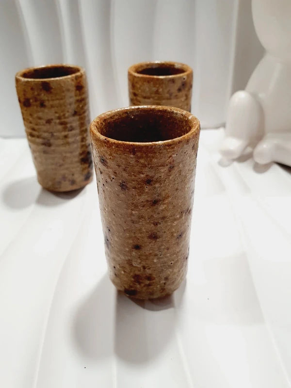 Lot de 3 petits gobelets cylindriques en grès pyrité vintage fait main des années 1970 aux nuances ocres et brunes mouchetées avec une finition vernissée brillante.