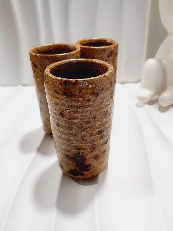 Lot de 3 petits gobelets cylindriques en grès pyrité vintage fait main des années 1970 aux nuances ocres et brunes mouchetées avec une finition vernissée brillante.
