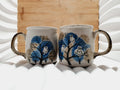 Deux mugs vintage en grès de la marque japonaise Otagiri avec un décor en relief de chouettes blanches dans les arbres sur fond bleu et beige