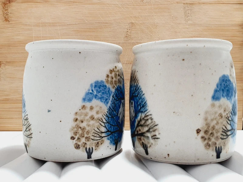 Deux mugs vintage en grès de la marque japonaise Otagiri avec un décor en relief de chouettes blanches dans les arbres sur fond bleu et beige.