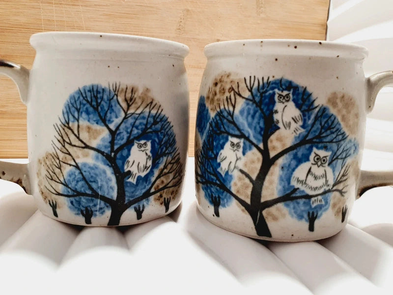 Deux mugs vintage en grès de la marque japonaise Otagiri avec un décor en relief de chouettes blanches dans les arbres sur fond bleu et beige.