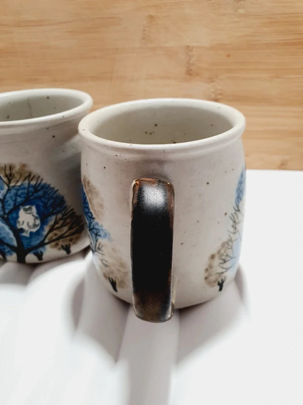 Deux mugs vintage en grès de la marque japonaise Otagiri avec un décor en relief de chouettes blanches dans les arbres sur fond bleu et beige.