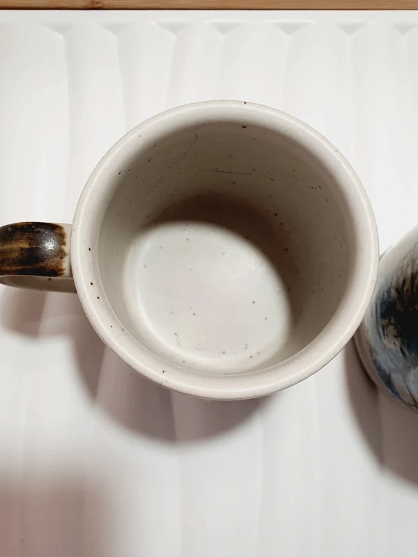 Deux mugs vintage en grès de la marque japonaise Otagiri avec un décor en relief de chouettes blanches dans les arbres sur fond bleu et beige.