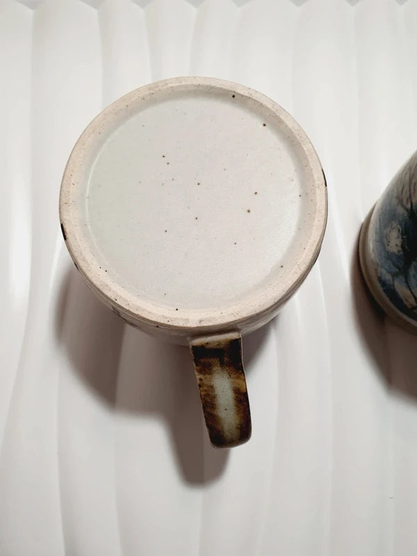 Deux mugs vintage en grès de la marque japonaise Otagiri avec un décor en relief de chouettes blanches dans les arbres sur fond bleu et beige.