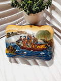 Boîte à bijoux rectangulaire festonnée en porcelaine vintage style Satsuma des années 1970 avec un couvercle illustré d'une scène traditionnelle de femmes et fillette sur une pirogue, richement décorée de fleurs colorées et de détails dorés à l'or fin, montrant le dessous estampillé d'une étiquette rouge Made in China Satsuma.