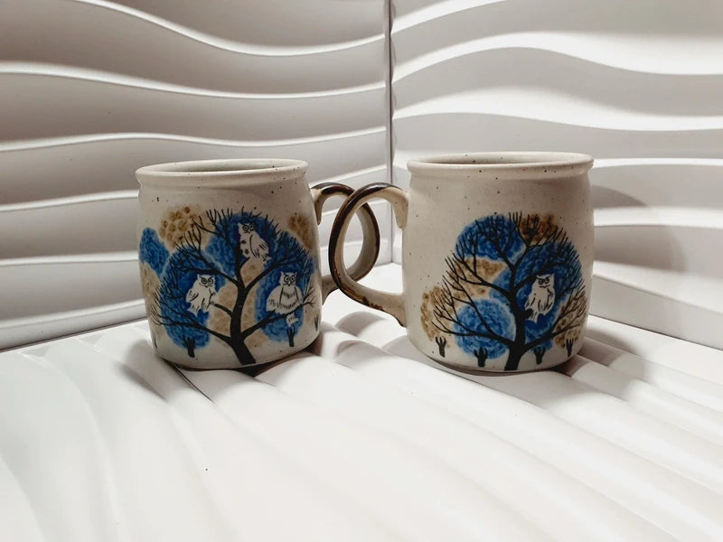Deux mugs vintage en grès de la marque japonaise Otagiri avec un décor en relief de chouettes blanches dans les arbres sur fond bleu et beige.