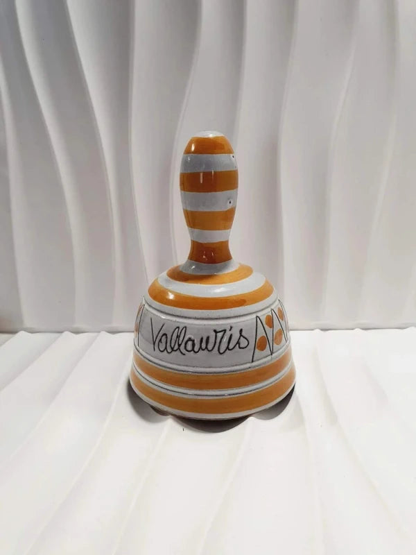 Cloche de table vintage à main en céramique de Vallauris des années 1970 avec des décors graphiques de rayures jaune et orangé sur fond écru, portant l'inscription signature Vallauris peinte à la main au dos et montrant son battant intérieur d'origine.