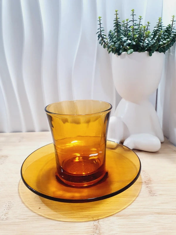Tasse haute de forme gobelet sans anse et sa sous-tasse assortie en verre trempé de couleur ambrée transparente, de la marque Duralex France époque années 1970.