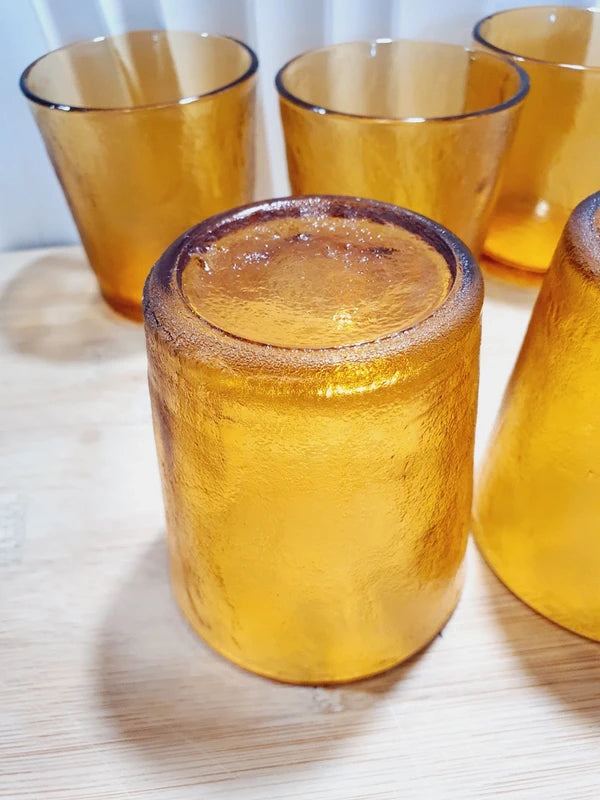 Lot de cinq verres gobelets et photophores vintage des années 1970 en verre épais teinté ambré transparent, avec une texture extérieure givrée effet écorce, style déco bohème chic.