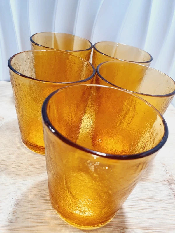 Lot de cinq verres gobelets et photophores vintage des années 1970 en verre épais teinté ambré transparent, avec une texture extérieure givrée effet écorce, style déco bohème chic.