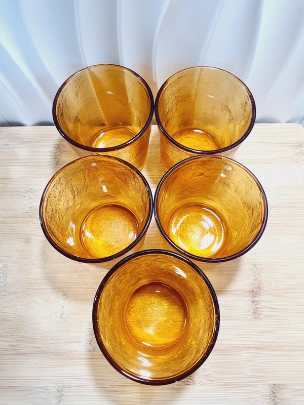 Lot de cinq verres gobelets et photophores vintage des années 1970 en verre épais teinté ambré transparent, avec une texture extérieure givrée effet écorce, style déco bohème chic.