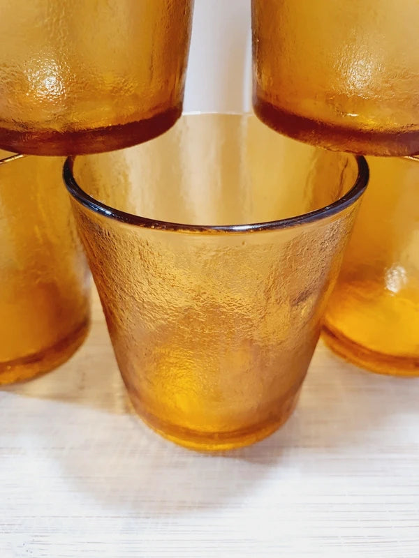 Lot de cinq verres gobelets et photophores vintage des années 1970 en verre épais teinté ambré transparent, avec une texture extérieure givrée effet écorce, style déco bohème chic.