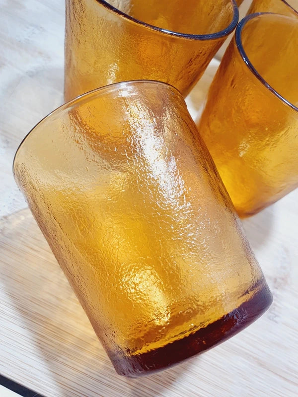 Lot de cinq verres gobelets et photophores vintage des années 1970 en verre épais teinté ambré transparent, avec une texture extérieure givrée effet écorce, style déco bohème chic.