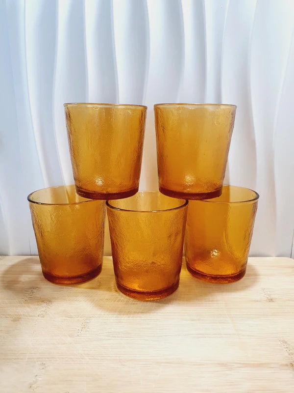 Lot de cinq verres gobelets et photophores vintage des années 1970 en verre épais teinté ambré transparent, avec une texture extérieure givrée effet écorce, style déco bohème chic.