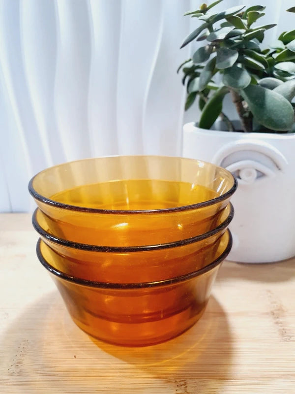 Lot de trois petits bols coupelles en verre trempé de couleur ambrée transparente, vaisselle de table de style pop épuré d'époque des années 1970 pour la décoration.