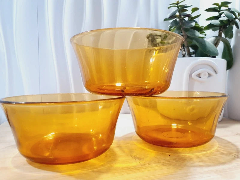 Lot de trois petits bols coupelles en verre trempé de couleur ambrée transparente, vaisselle de table de style pop épuré d'époque des années 1970 pour la décoration.