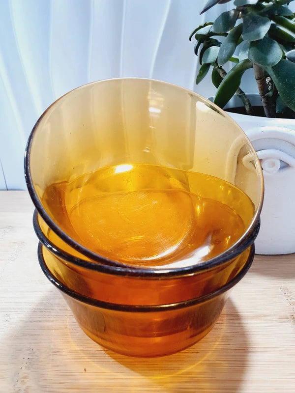 Lot de trois petits bols coupelles en verre trempé de couleur ambrée transparente, vaisselle de table de style pop épuré d'époque des années 1970 pour la décoration.