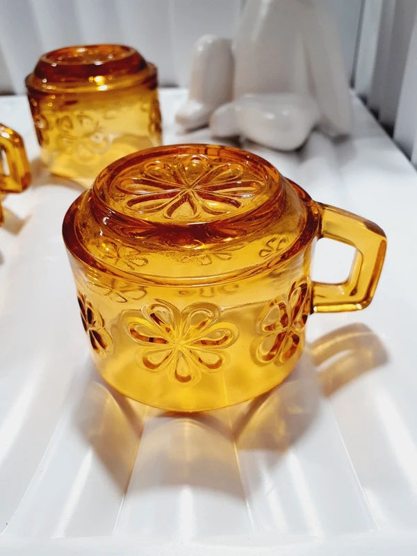 Lot de six tasses à café espresso empilables en verre trempé ambré transparent, ornées d'un motif de fleurs marguerites "Daisy" moulé en relief, marque Vereco France époque années 1970.