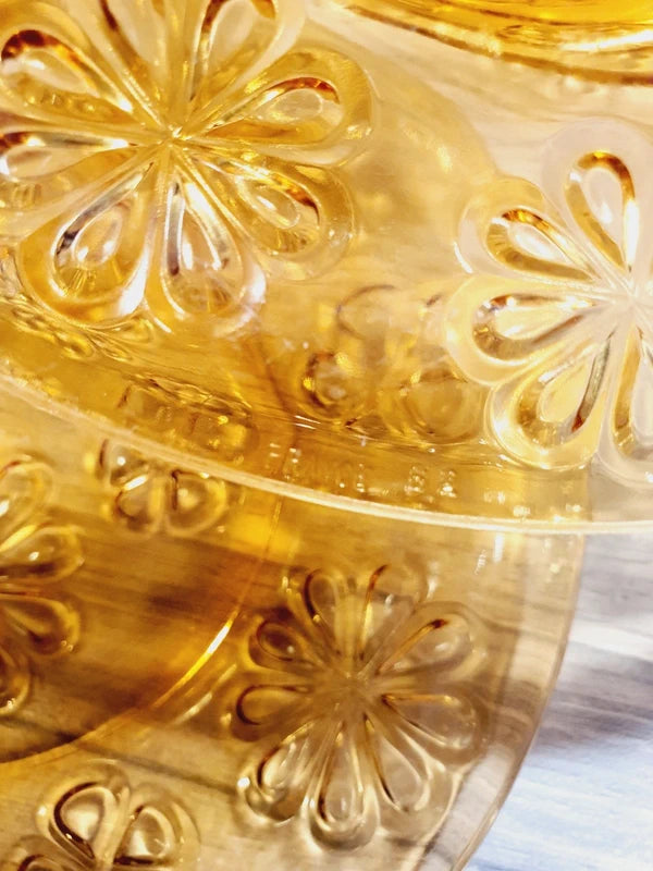 Lot de six assiettes plates rondes à dessert en verre trempé épais de couleur ambrée transparente, ornées d'un motif de fleurs marguerites moulé en relief sur l'extérieur, de la marque française Vereco époque années 1970.