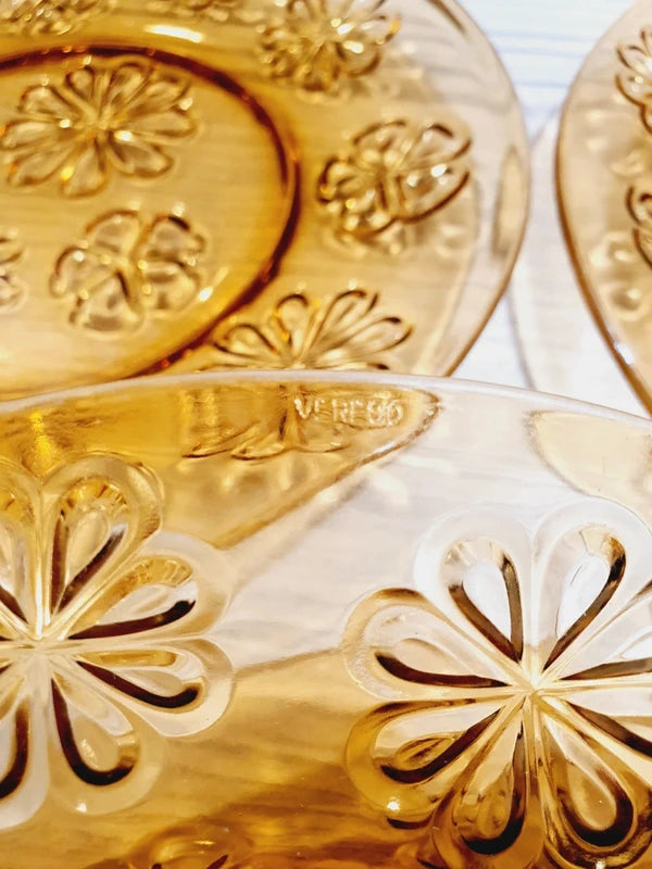 Lot de six assiettes plates rondes à dessert en verre trempé épais de couleur ambrée transparente, ornées d'un motif de fleurs marguerites moulé en relief sur l'extérieur, de la marque française Vereco époque années 1970.