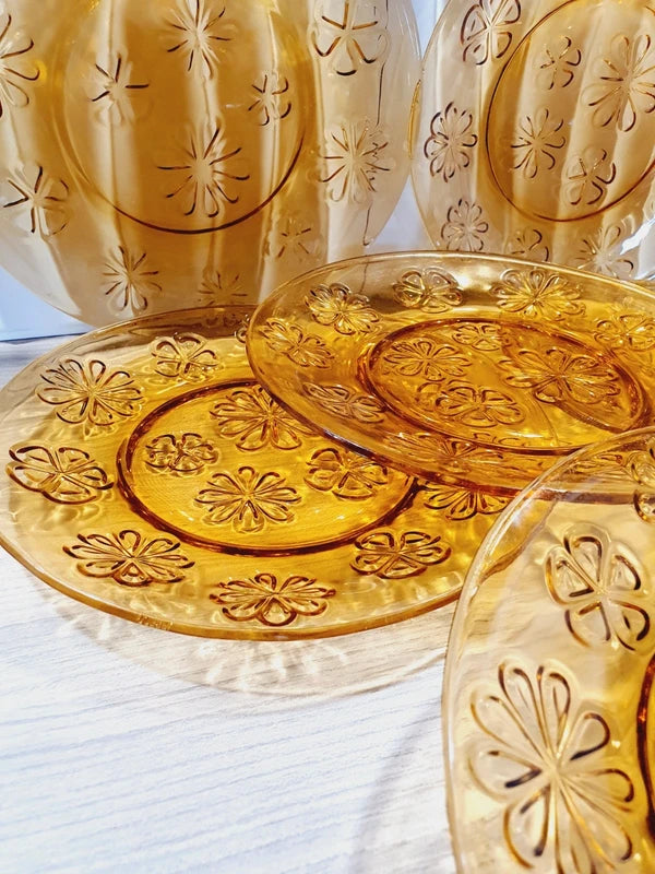 Lot de six assiettes plates rondes à dessert en verre trempé épais de couleur ambrée transparente, ornées d'un motif de fleurs marguerites moulé en relief sur l'extérieur, de la marque française Vereco époque années 1970.