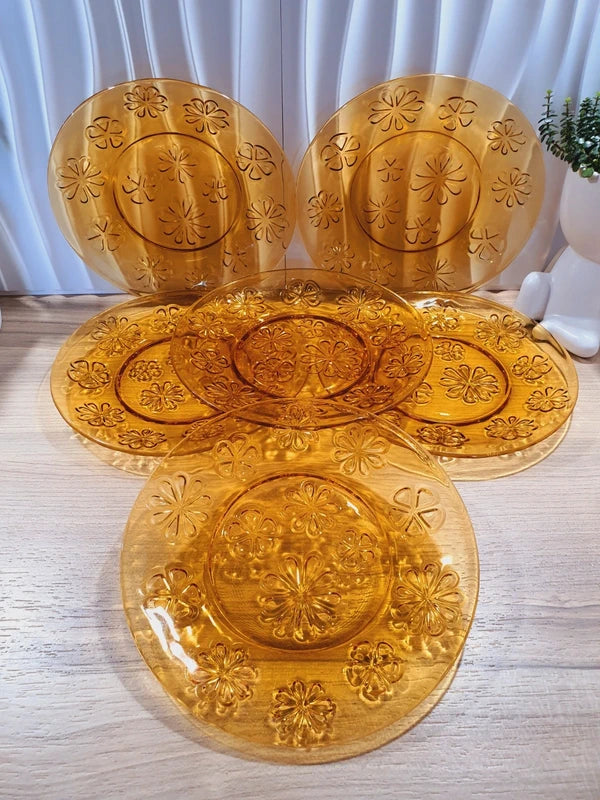 Lot de six assiettes plates rondes à dessert en verre trempé épais de couleur ambrée transparente, ornées d'un motif de fleurs marguerites moulé en relief sur l'extérieur, de la marque française Vereco époque années 1970.
