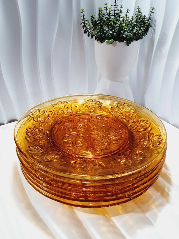 Lot de six assiettes plates rondes à dessert en verre trempé épais de couleur ambrée transparente, ornées d'un motif de fleurs marguerites moulé en relief sur l'extérieur, de la marque française Vereco époque années 1970.