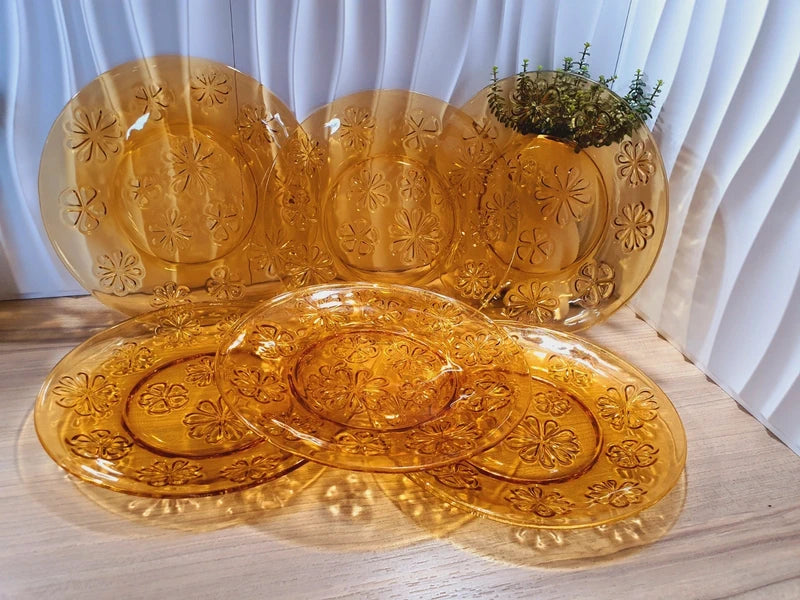 Lot de six assiettes plates rondes à dessert en verre trempé épais de couleur ambrée transparente, ornées d'un motif de fleurs marguerites moulé en relief sur l'extérieur, de la marque française Vereco époque années 1970.