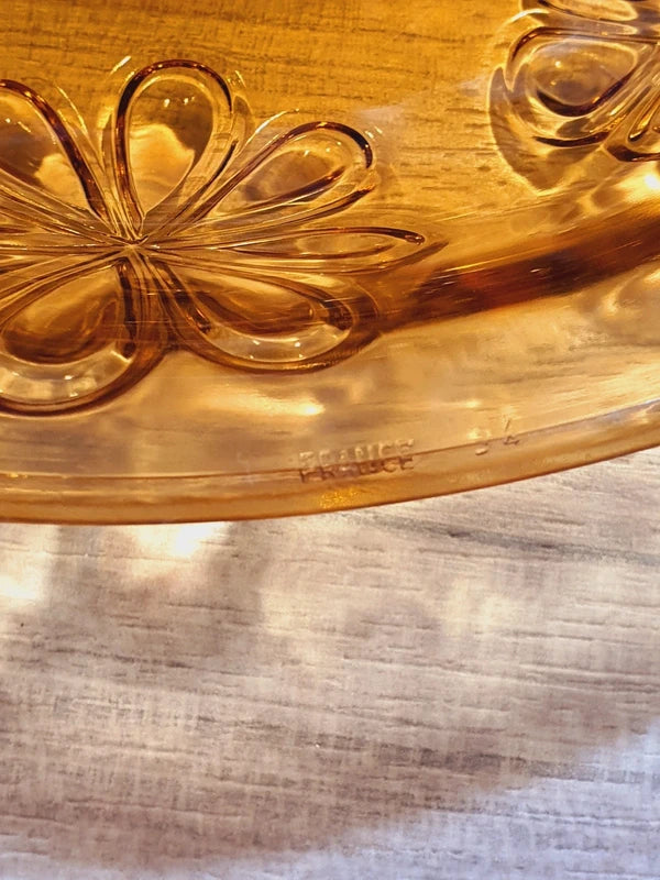 Grand plat rond creux à salade en verre trempé épais couleur ambre transparent, orné d'un motif de fleurs marguerites moulé en relief sur le dessous, de la marque Vereco France époque années 1970.