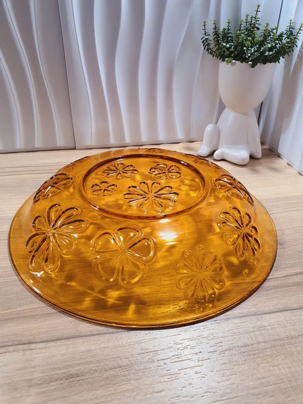 Grand plat rond creux à salade en verre trempé épais couleur ambre transparent, orné d'un motif de fleurs marguerites moulé en relief sur le dessous, de la marque Vereco France époque années 1970.