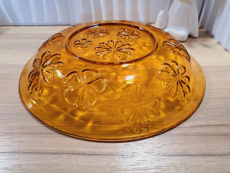 Grand plat rond creux à salade en verre trempé épais couleur ambre transparent, orné d'un motif de fleurs marguerites moulé en relief sur le dessous, de la marque Vereco France époque années 1970.