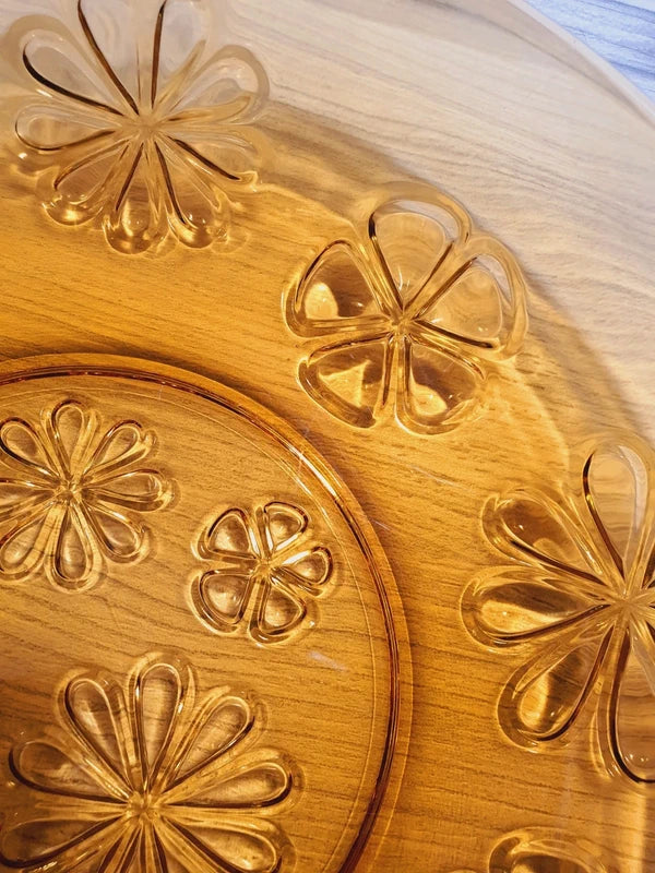 Grand plat rond creux à salade en verre trempé épais couleur ambre transparent, orné d'un motif de fleurs marguerites moulé en relief sur le dessous, de la marque Vereco France époque années 1970.