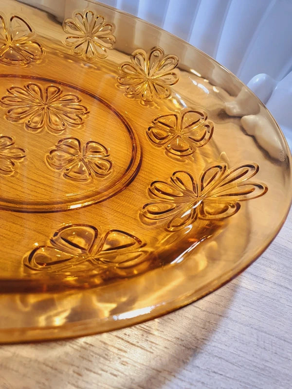 Grand plat rond creux à salade en verre trempé épais couleur ambre transparent, orné d'un motif de fleurs marguerites moulé en relief sur le dessous, de la marque Vereco France époque années 1970.