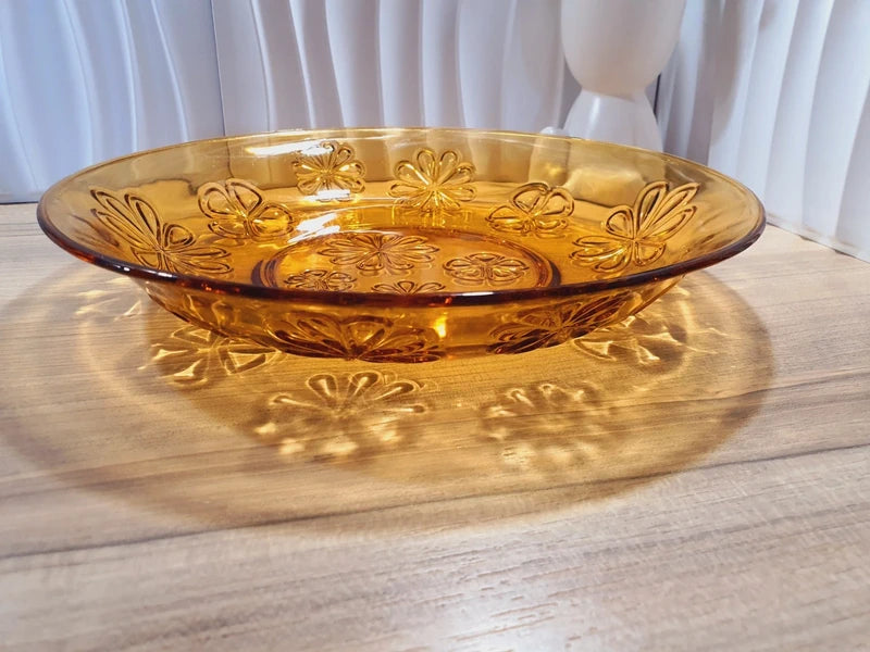 Grand plat rond creux à salade en verre trempé épais couleur ambre transparent, orné d'un motif de fleurs marguerites moulé en relief sur le dessous, de la marque Vereco France époque années 1970.