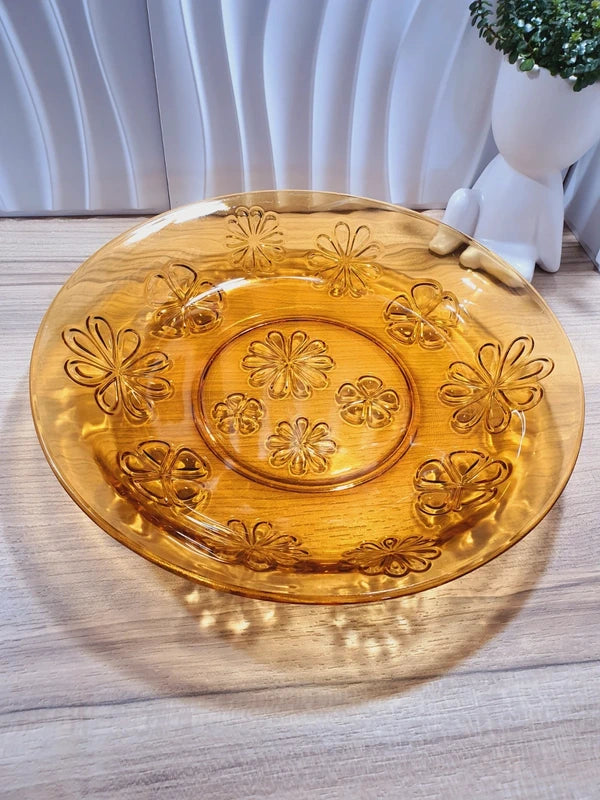 Grand plat rond creux à salade en verre trempé épais couleur ambre transparent, orné d'un motif de fleurs marguerites moulé en relief sur le dessous, de la marque Vereco France époque années 1970.