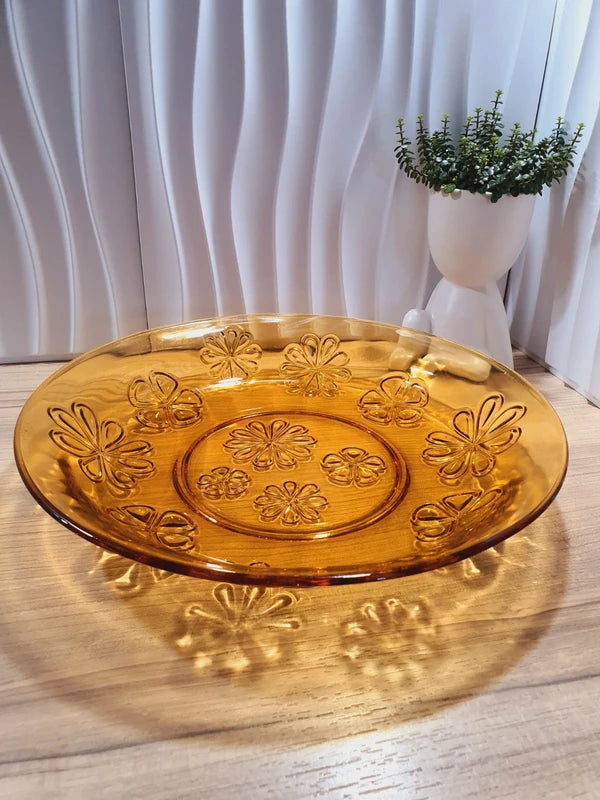 Grand plat rond creux à salade en verre trempé épais couleur ambre transparent, orné d'un motif de fleurs marguerites moulé en relief sur le dessous, de la marque Vereco France époque années 1970.